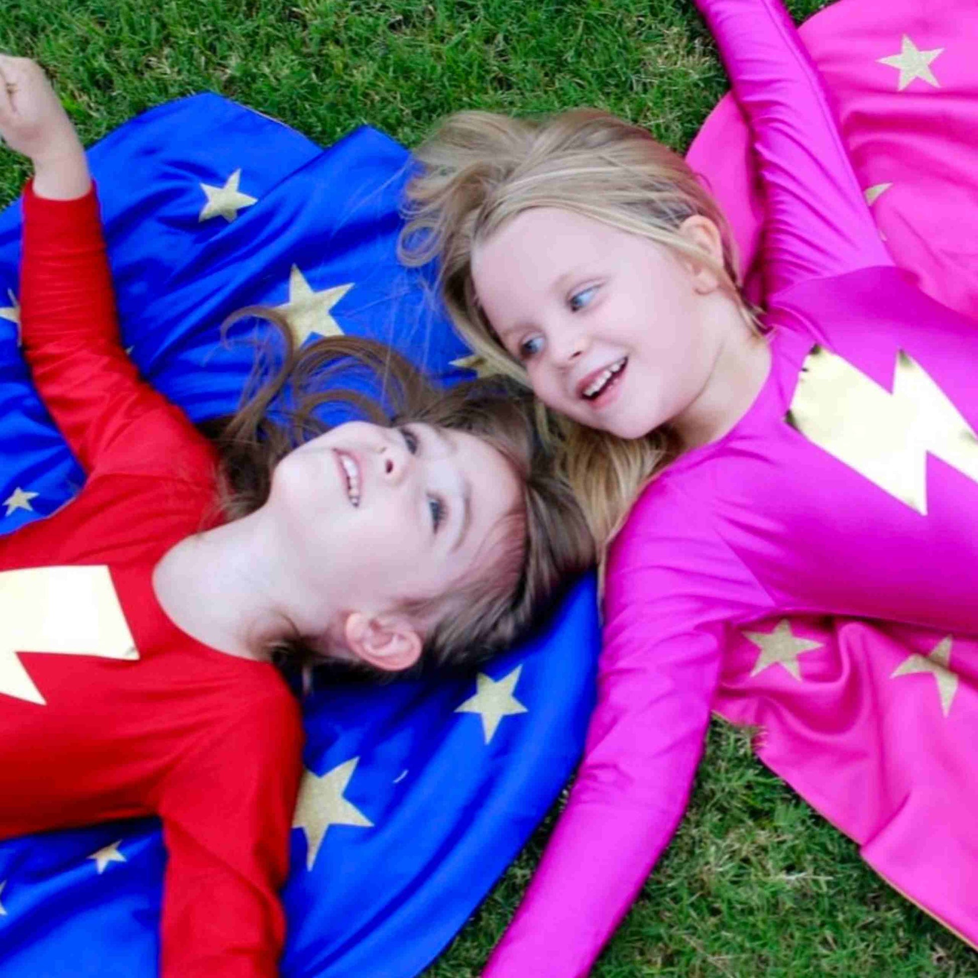 two girls in costumes laying on a blanket