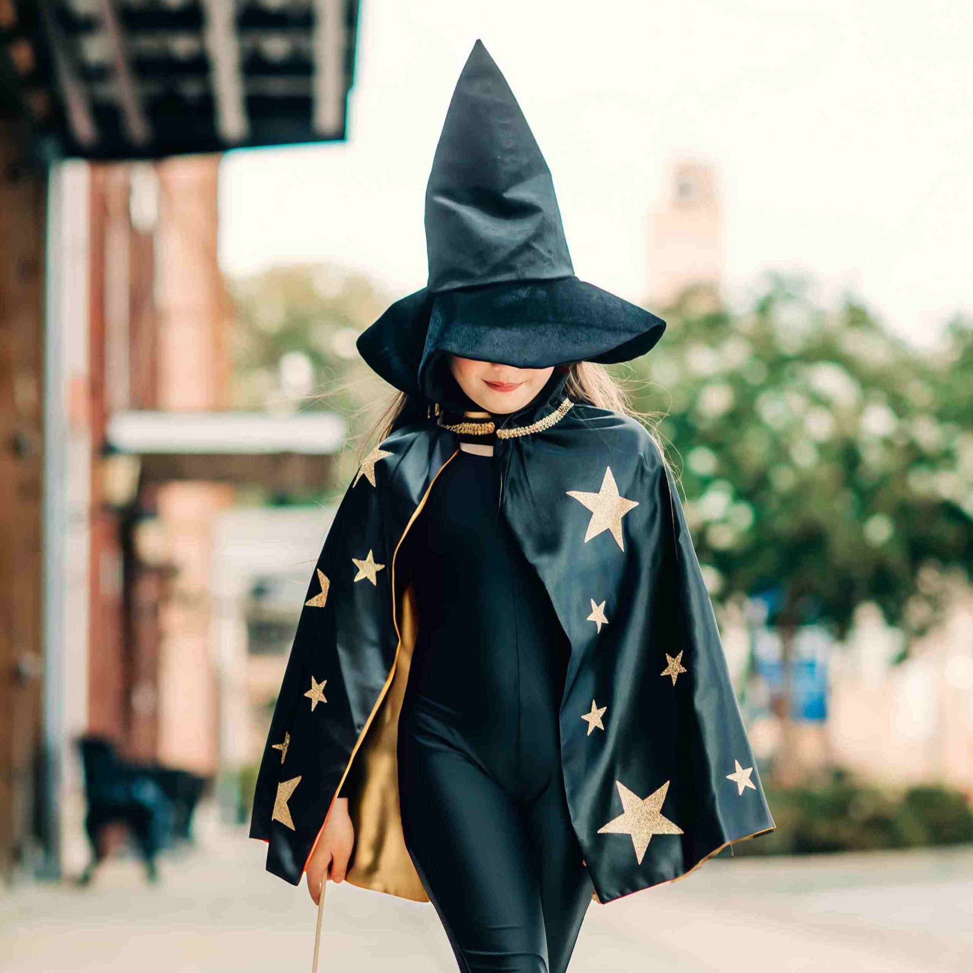 a woman in a black witches costume walking down the street