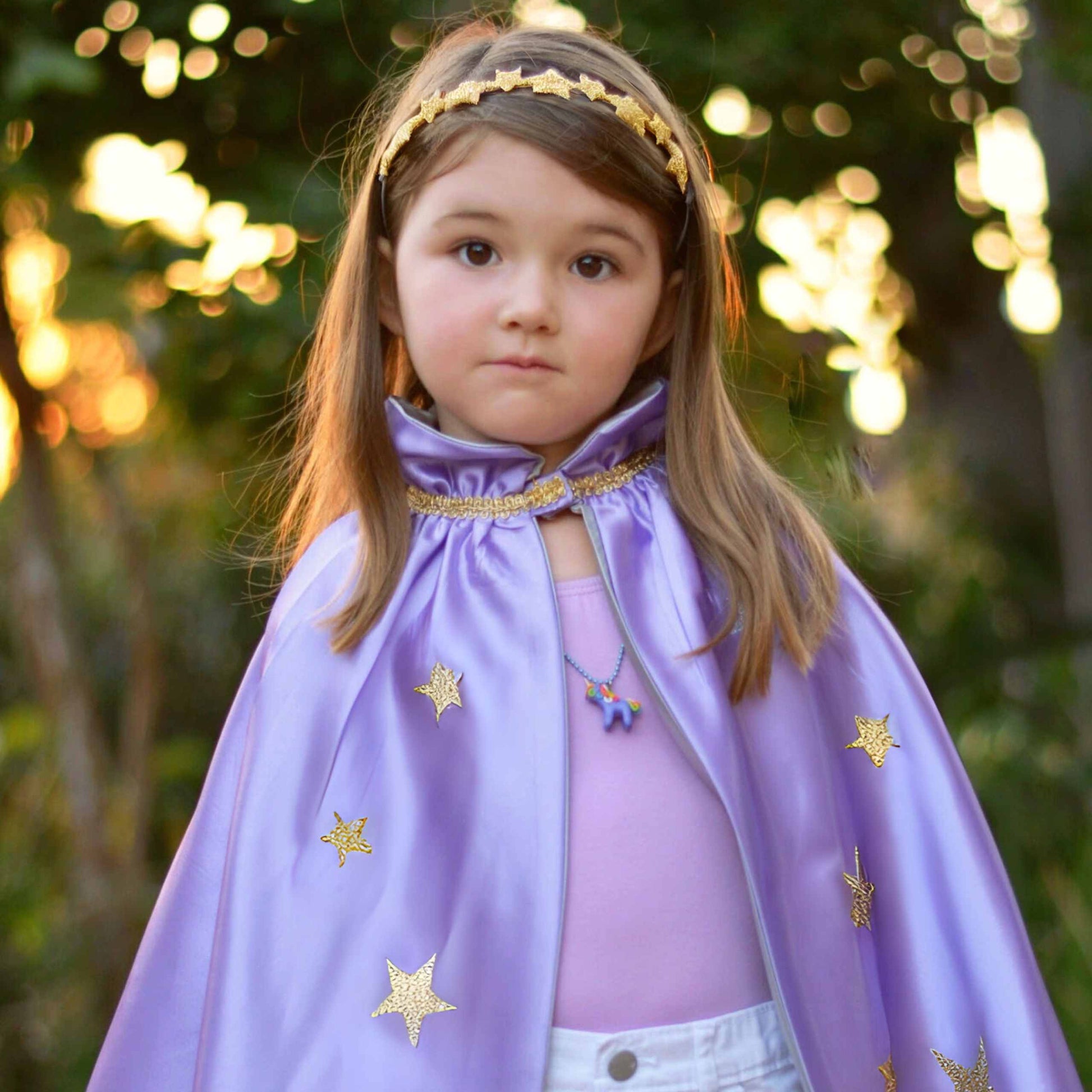 a little girl dressed in a purple cape