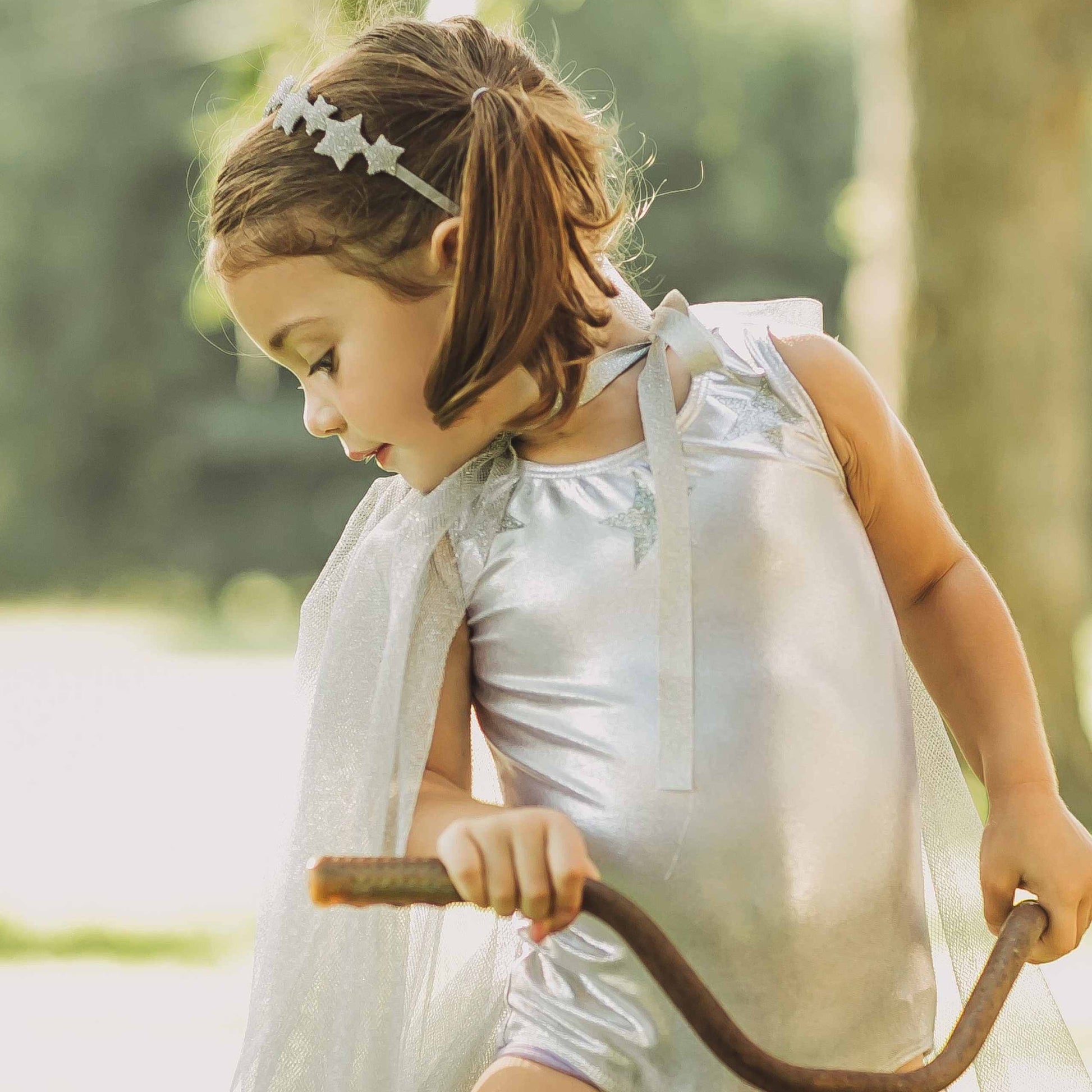 a little girl in a white dress holding a stick