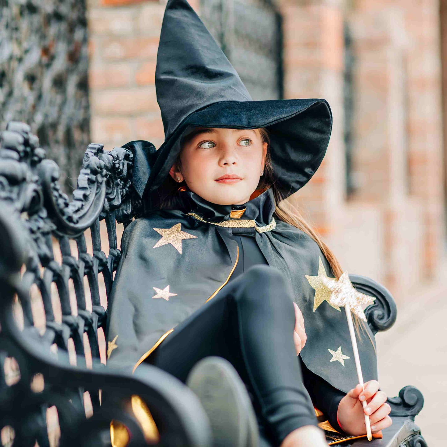 a little girl dressed as a wizard sitting on a bench