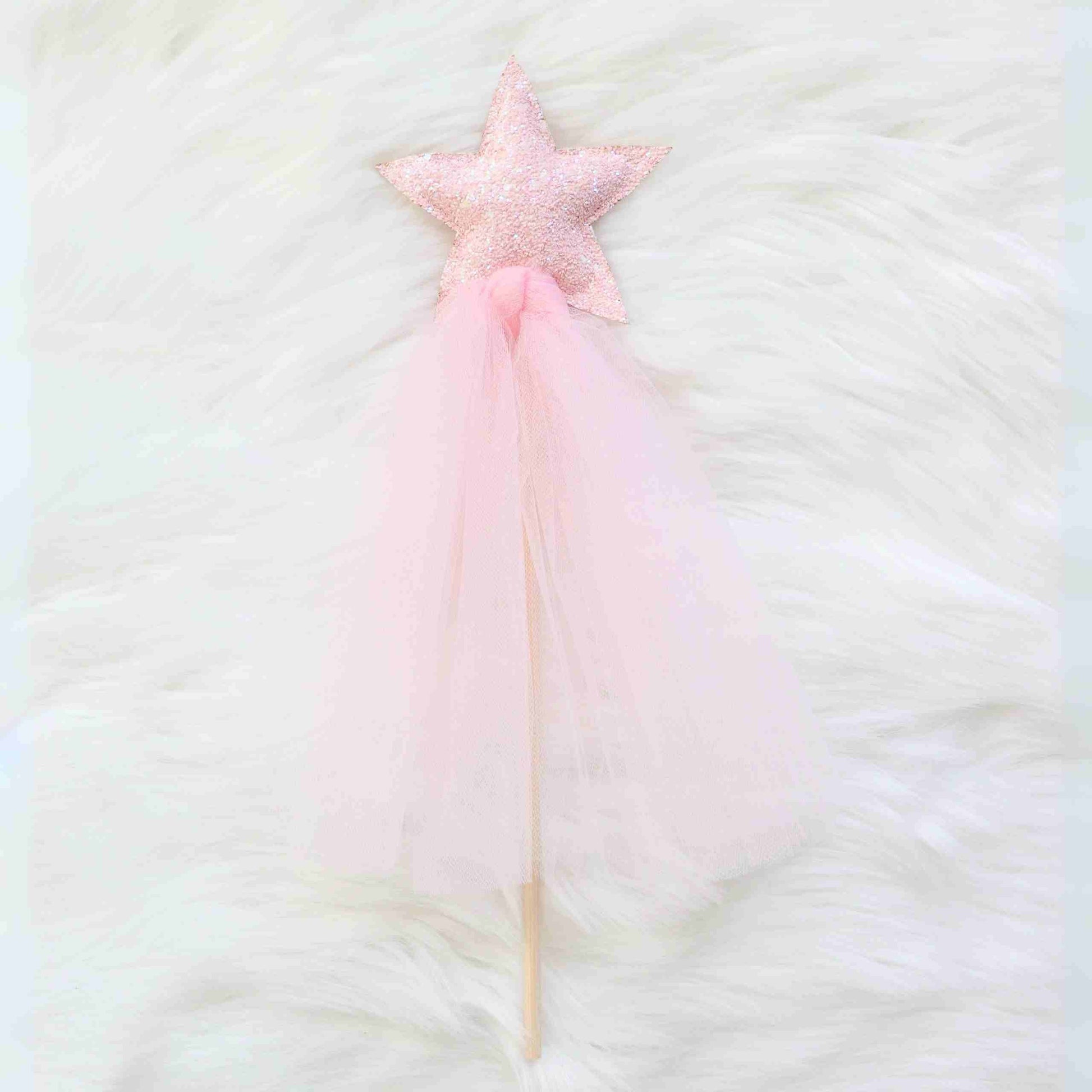 a pink star wand on a white fur background